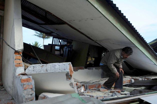 An Acehnese man makes his way under the collapsed roof of a building after it was destroyed
